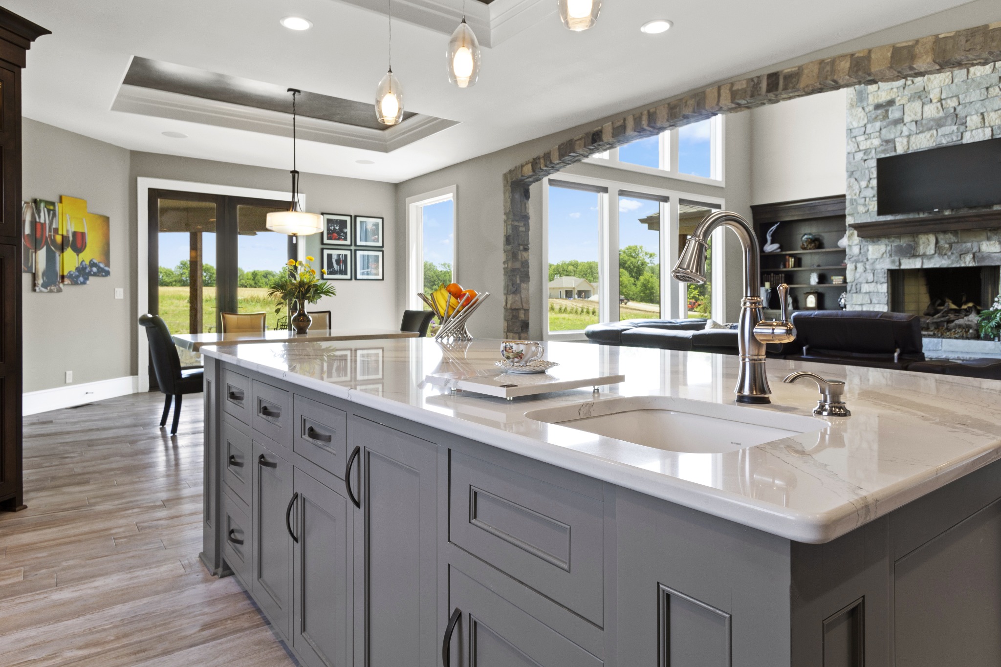 A luxury kitchen with gray cabinets and stone counters.