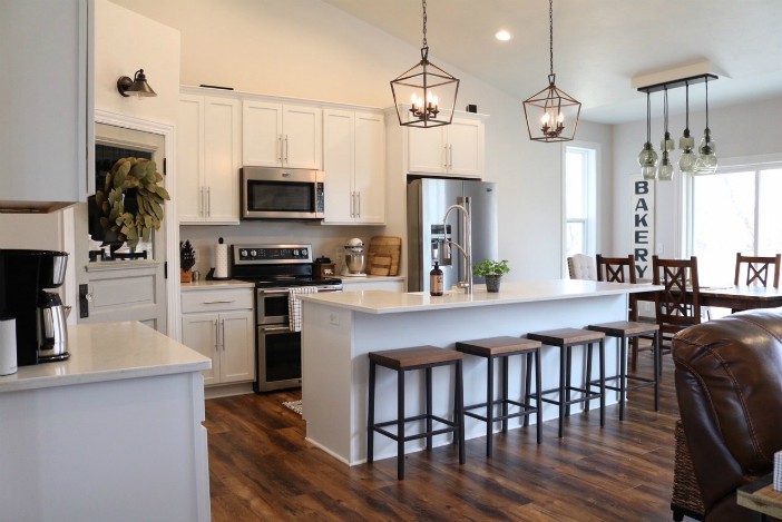 A beautiful kitchen with white cabinets and dark wooden floors.