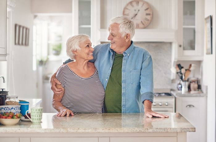 elderly couple embracing one another in a kitchen area