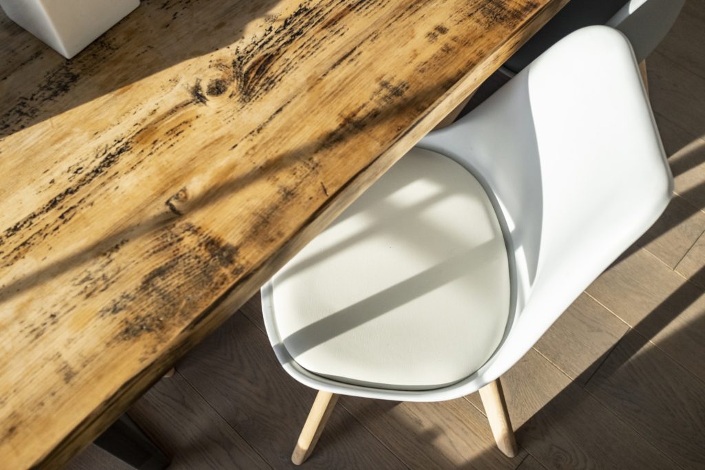A reclaimed wood table with a white mid-century modern egg chair.