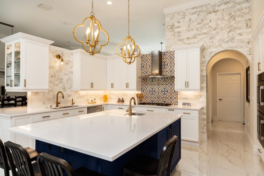 A mediterranean style kitchen with unique backsplash and marble counters.