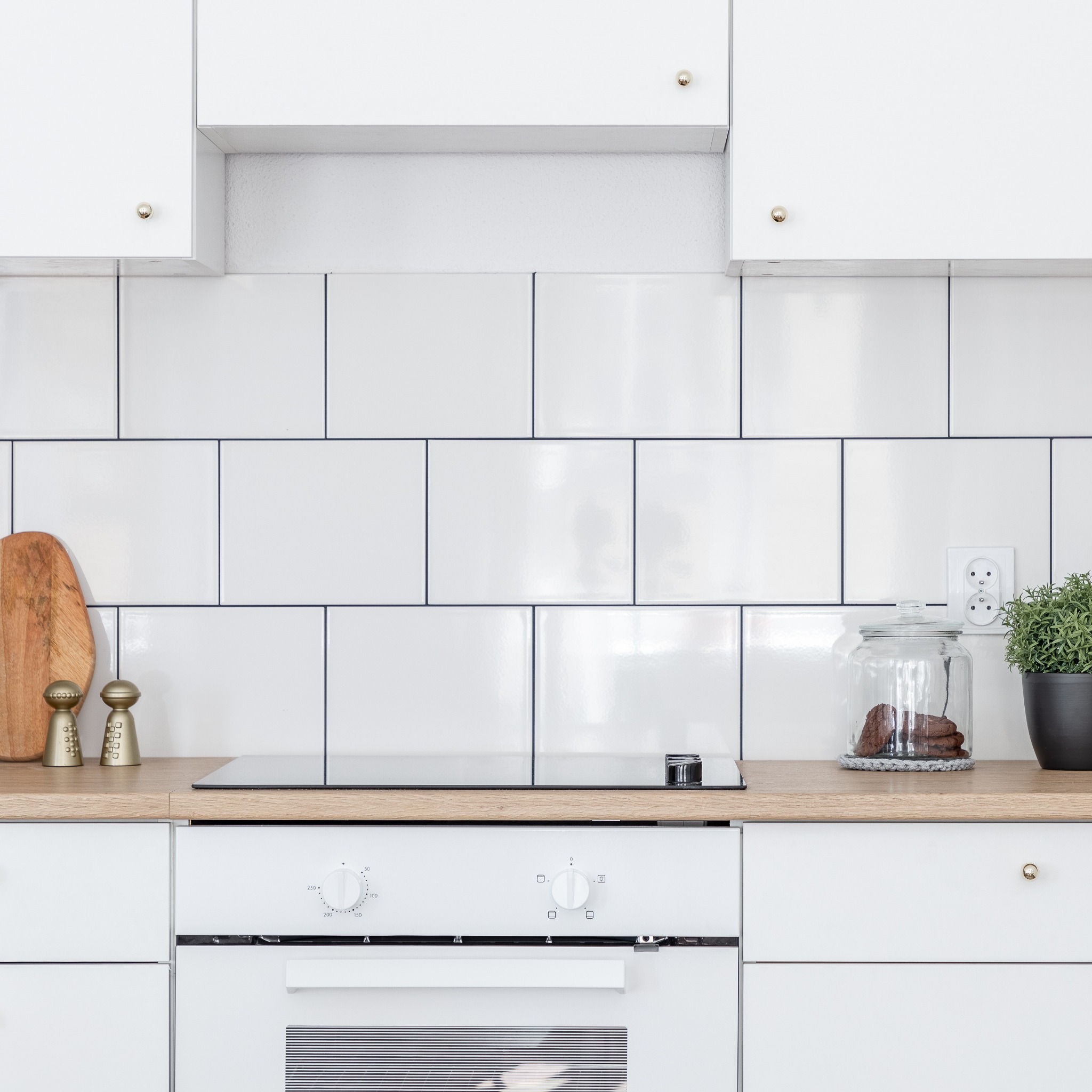 A white kitchen with a square tile backsplash/