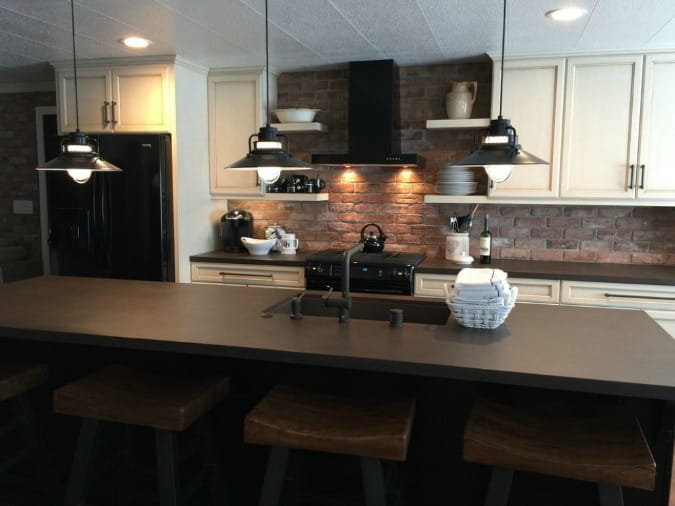 A Kitchen with a dark brick wall and dark brown Dekton countertops.