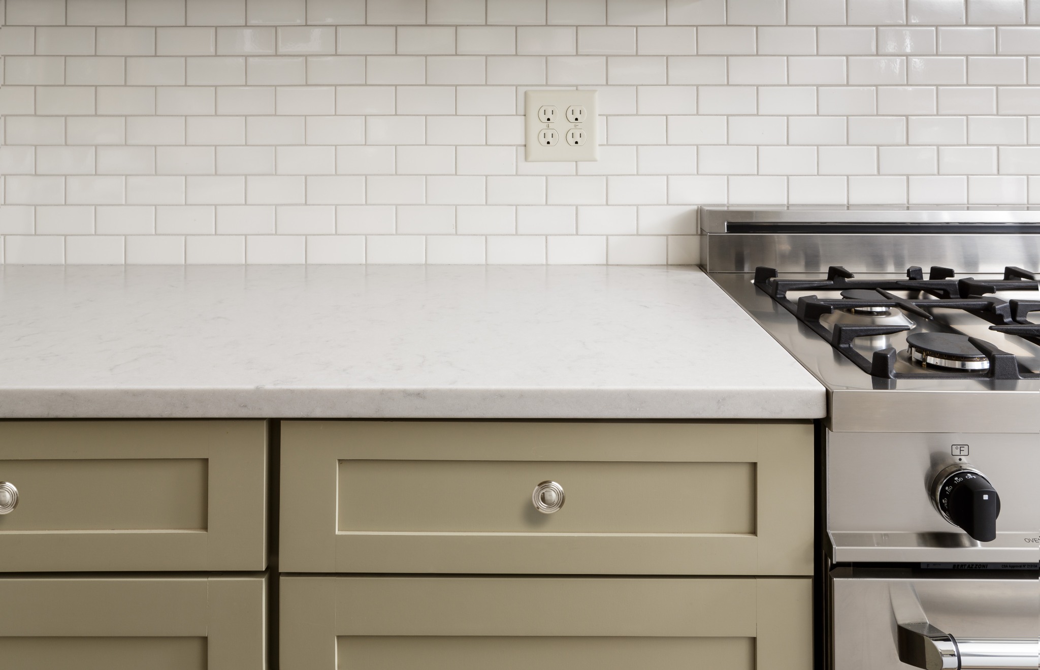 Khaki colored cabinets with white stone counters.
