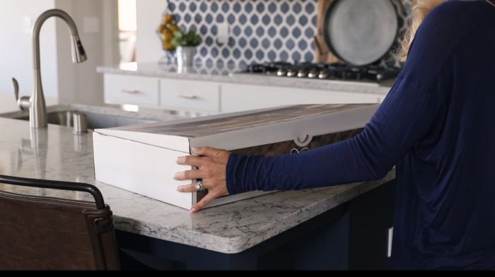 woman opening box on a stone countertop
