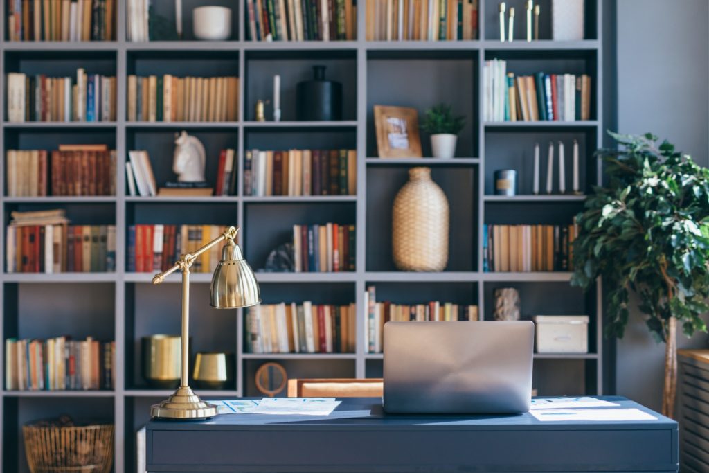 A luxury office with a style bookshelf behind the stone desk.