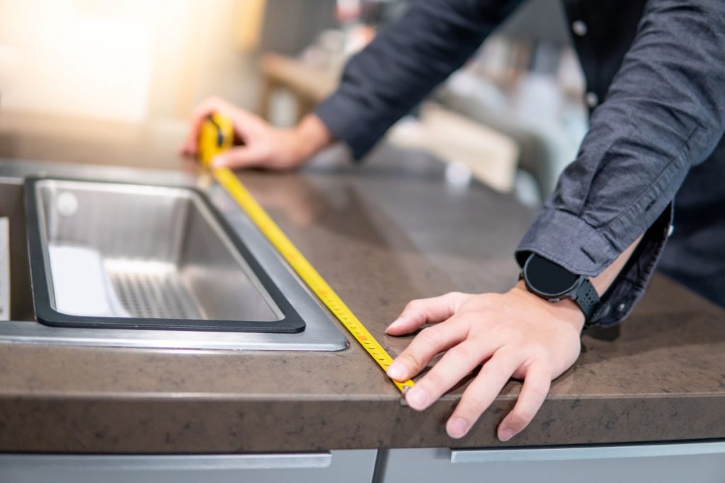 Someone measuring a counter top to install custom FeelsWarm countertop heating mats.